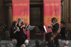 A string quartet plays on a stage in front of a Classical WETA banner
