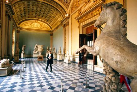 A tourist stands in the middle of a museum gallery.