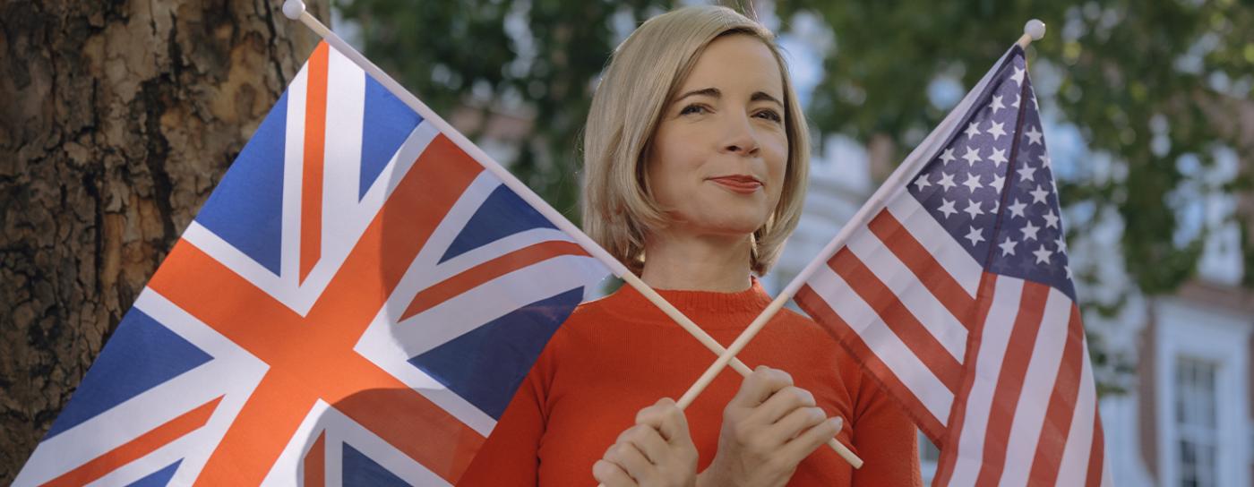 Lucy Worsley wearing red shirt and holding British and American flags
