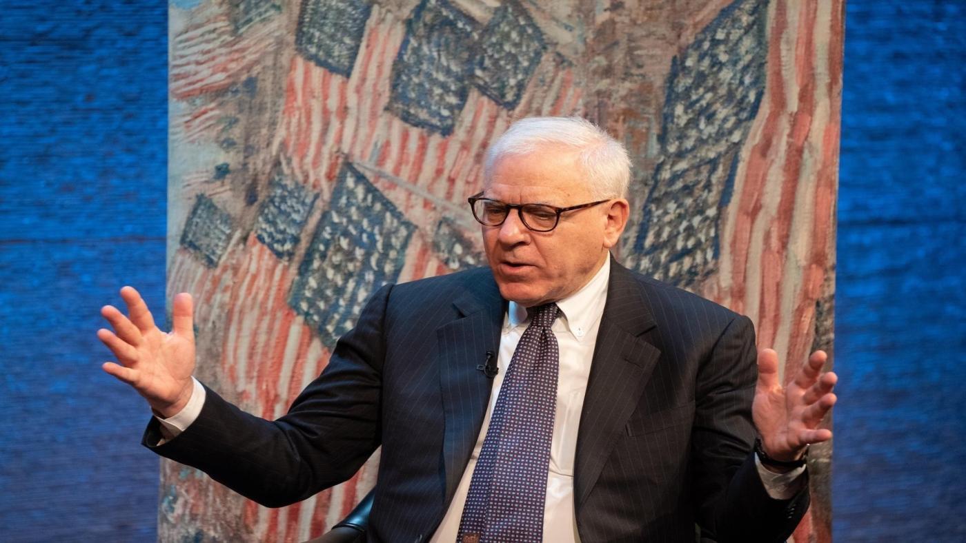 Henry David Rubenstein in front of American flag background