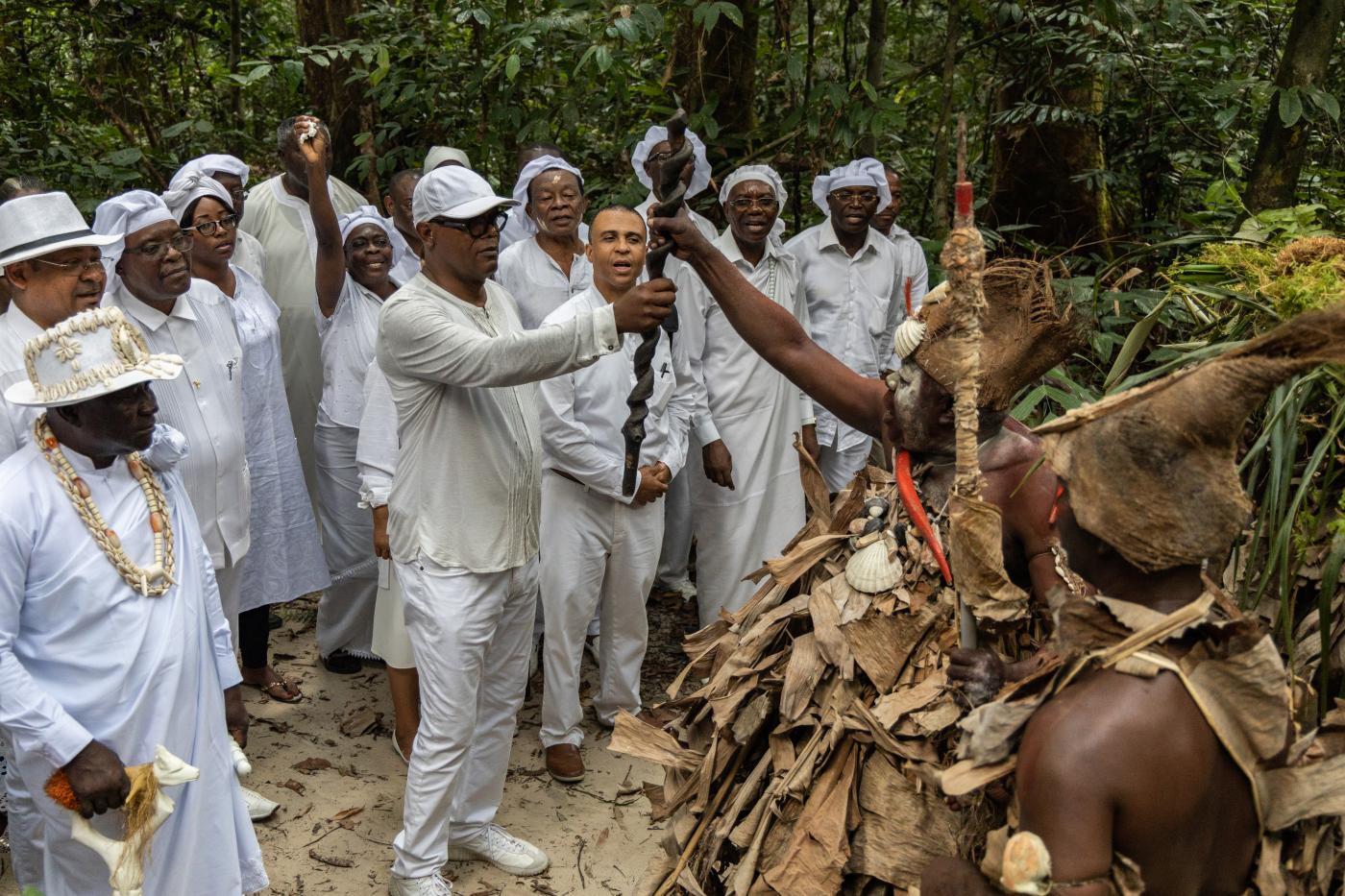 group of black and brown people in white attire participating in ritual